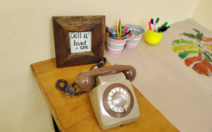 A picture of a phone on desk next to sign saying call a loved one